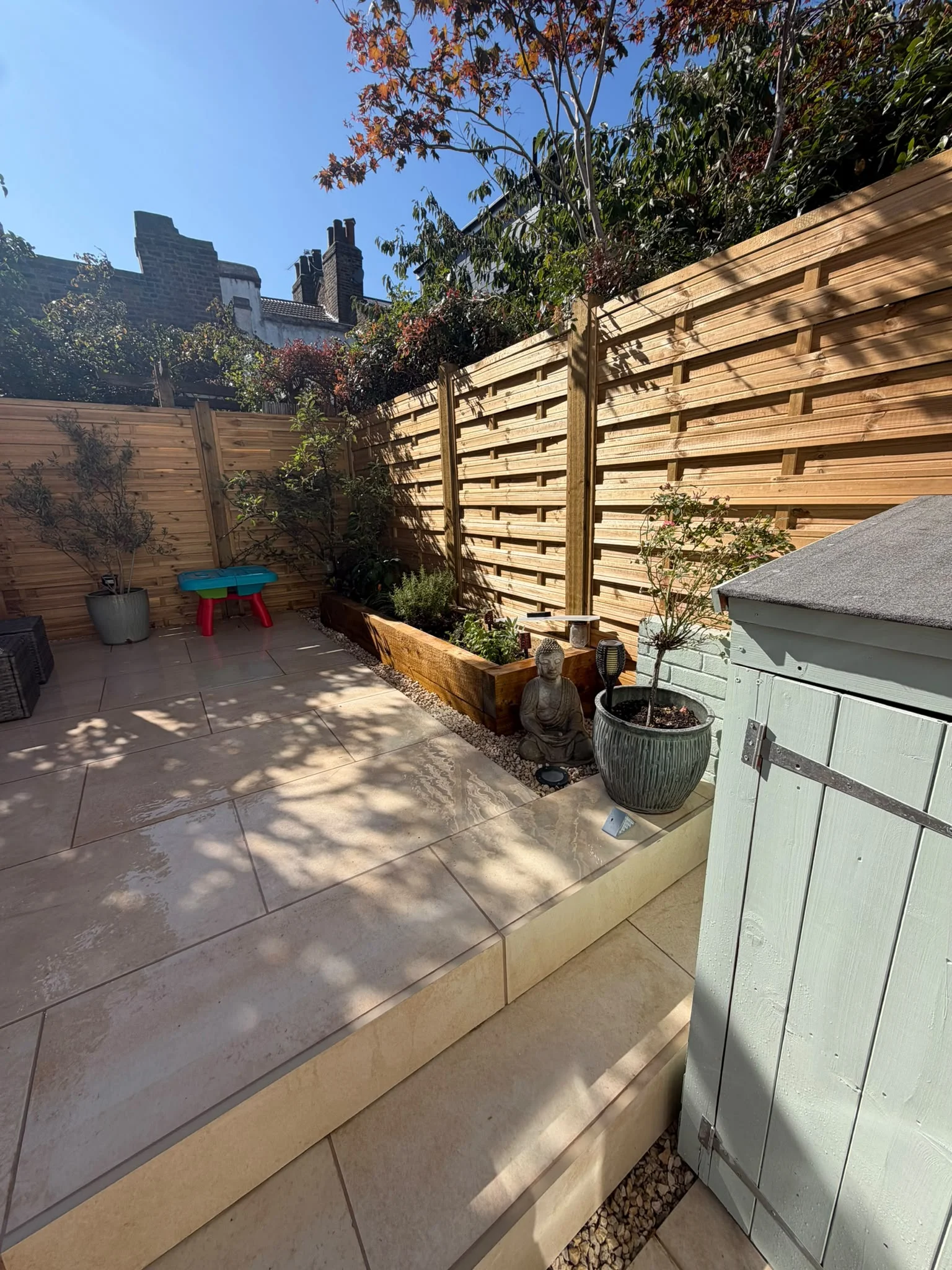 New porcelain paving, raised sleeper planter, new cedar fence panels and garden shed corner landscaped Greenwich garden